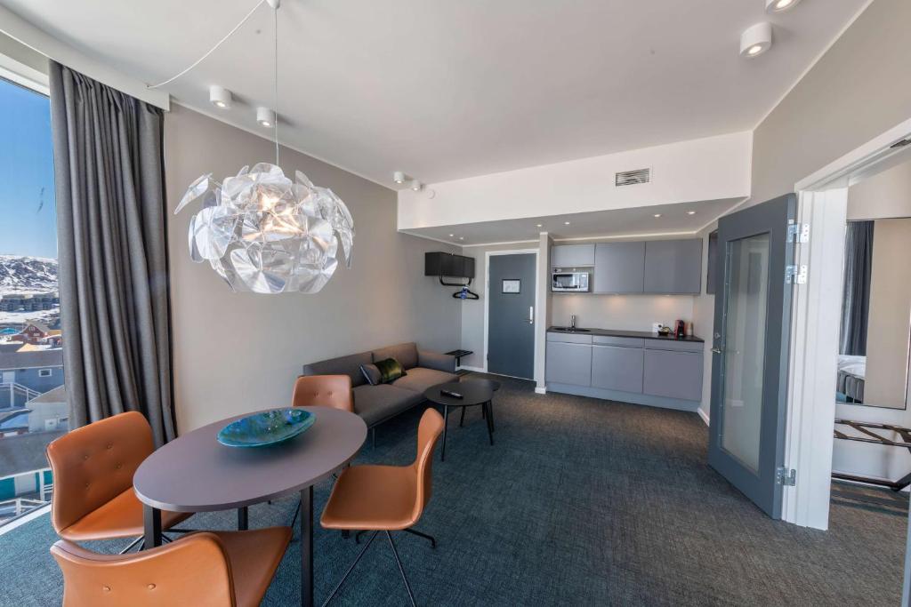 a living room with a table and chairs and a kitchen at Best Western Plus Hotel Ilulissat in Ilulissat