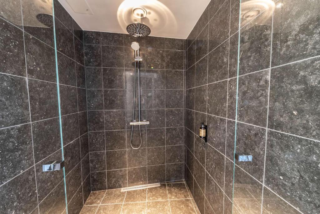 a bathroom with a shower with black tiles at Best Western Plus Hotel Ilulissat in Ilulissat