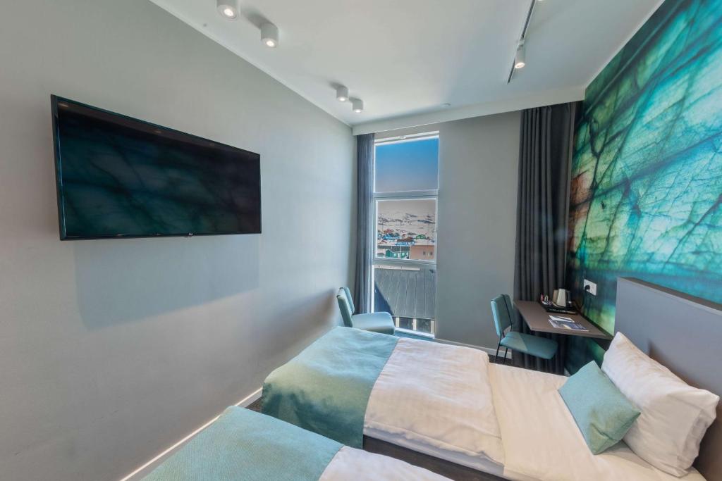 a hotel room with a bed and a desk and a window at Best Western Plus Hotel Ilulissat in Ilulissat