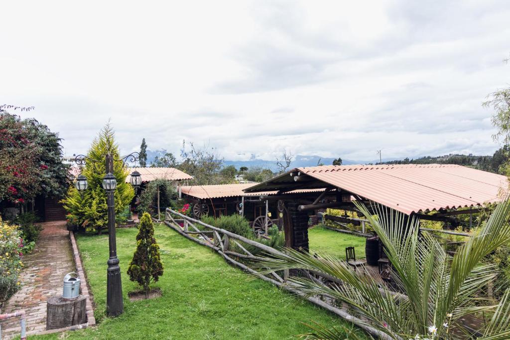 einen Garten mit einem Gebäude mit einem Dach in der Unterkunft Campo Wasi in Riobamba