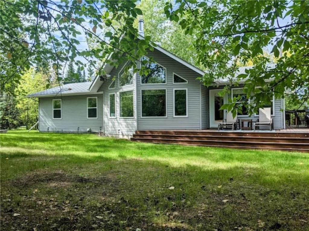 a white house with a porch and a yard at 3 Bedroom Cottage - Sunroom + Patio + Fire Pit in Grand Beach