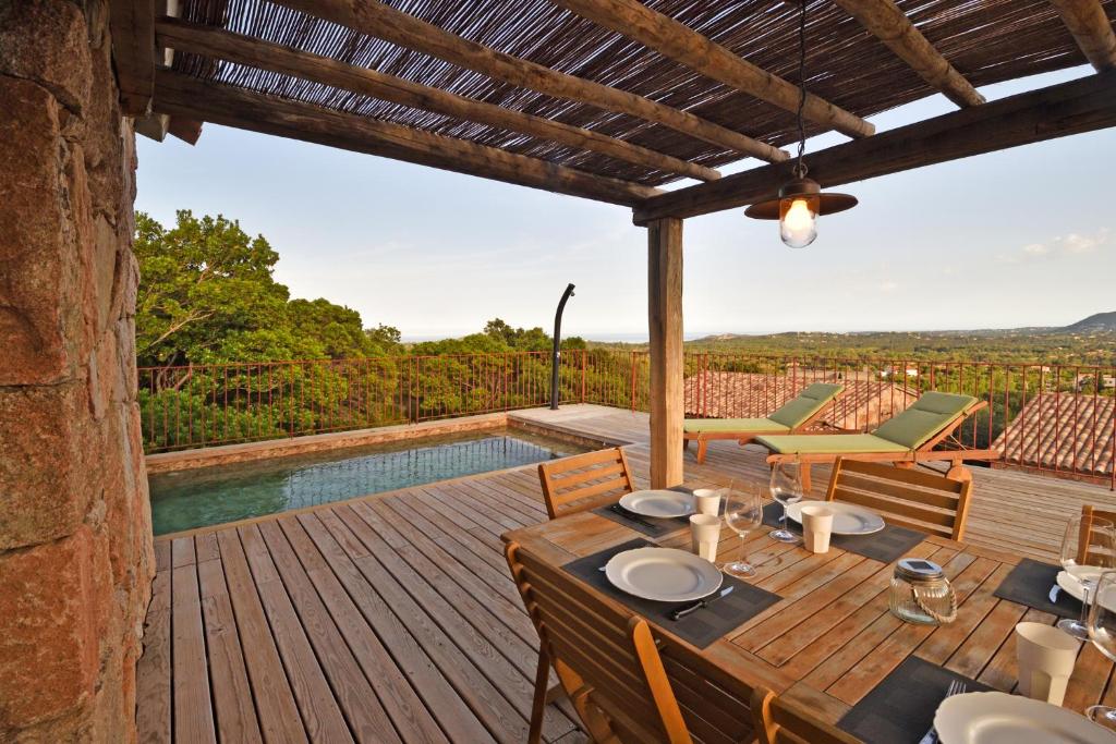 una terraza de madera con mesa, sillas y piscina en Bergeries de charme Caselle di Conca en Conca