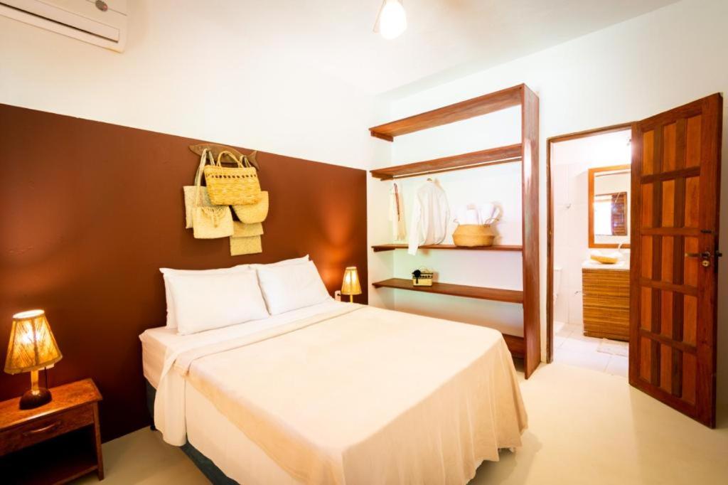 a bedroom with a large white bed and a bathroom at Casas e apartamentos da Ilda in Trancoso