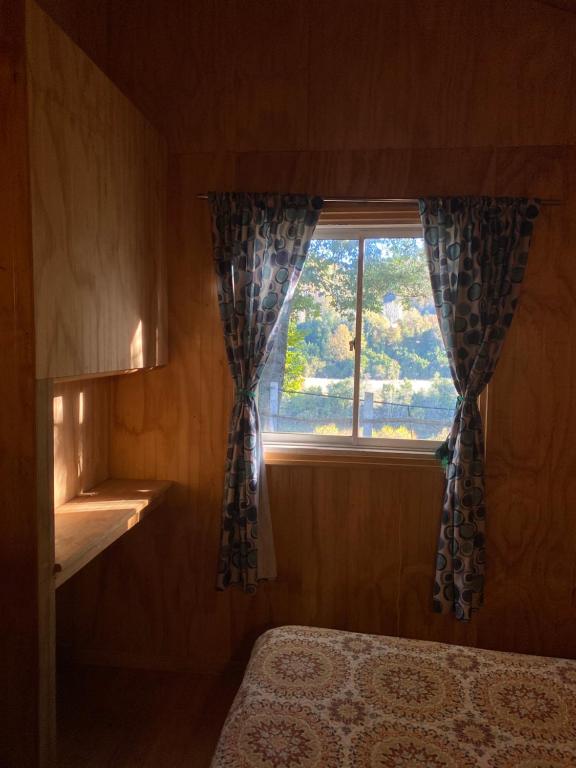 a bedroom with a window with curtains and a bed at Parcela borde rio in Villarrica