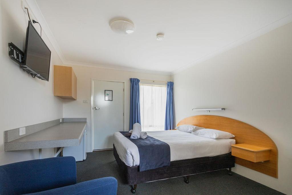 a hotel room with a bed and a television at The Busselton Motel in Busselton