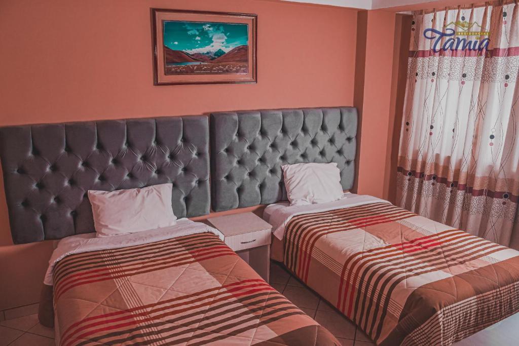 two beds in a room with pink walls at Hotel Residencial Tamia in Huaraz