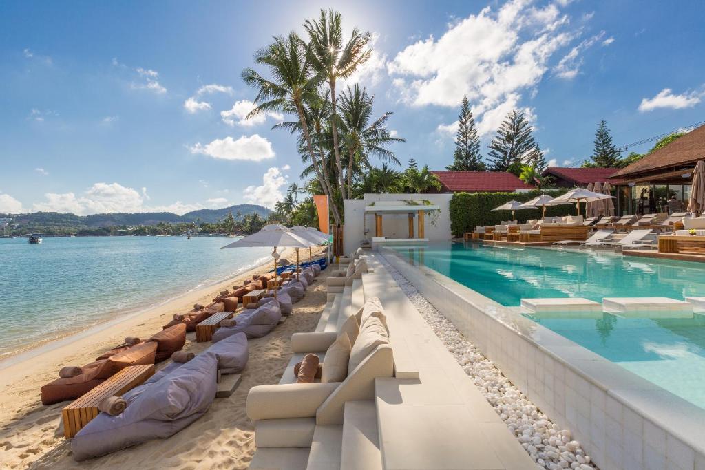 a resort infinity pool with lounge chairs and the ocean at Chi - The Residence in Bophut 