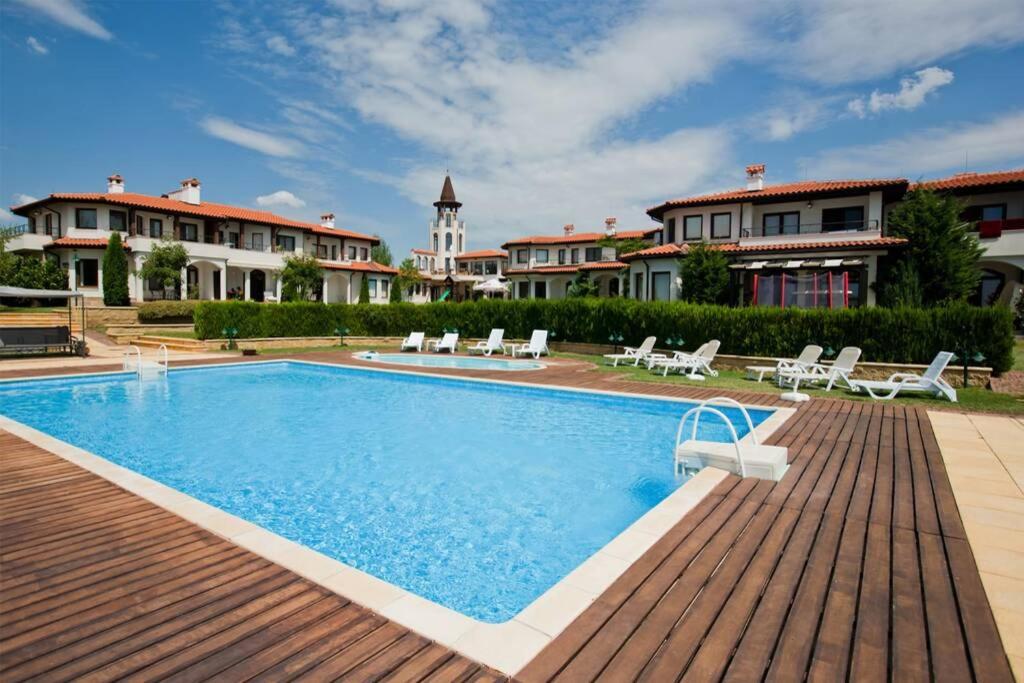 une grande piscine avec une terrasse en bois et certains bâtiments dans l'établissement Black Sea Rama Golf and Villas, Bell Tower, à Balchik
