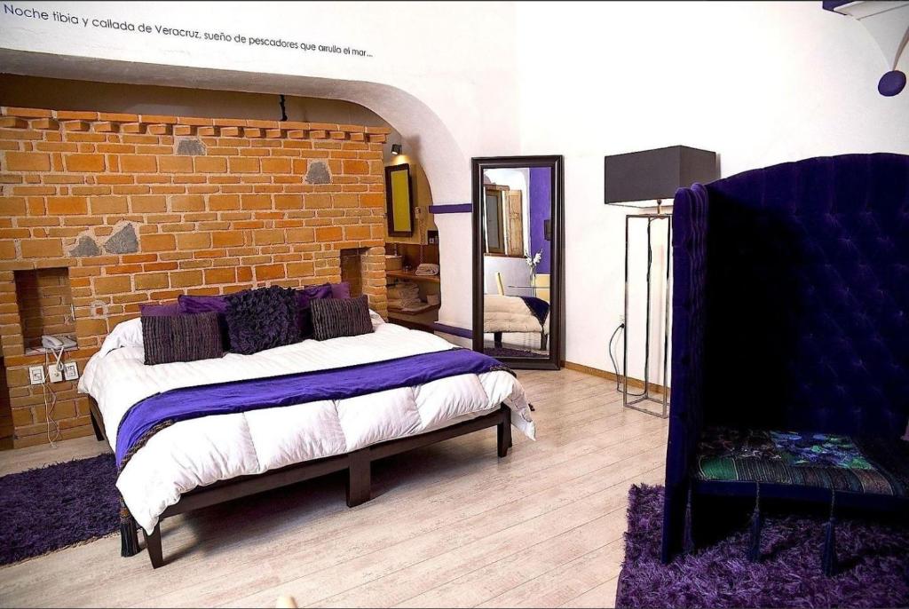 1 dormitorio con cama y pared de ladrillo en El Sueño Hotel & Spa, en Puebla