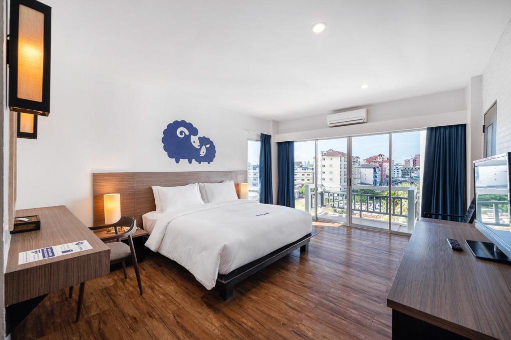 a bedroom with a bed and a large window with a view at Kokotel Pattaya South Beach in Pattaya Central