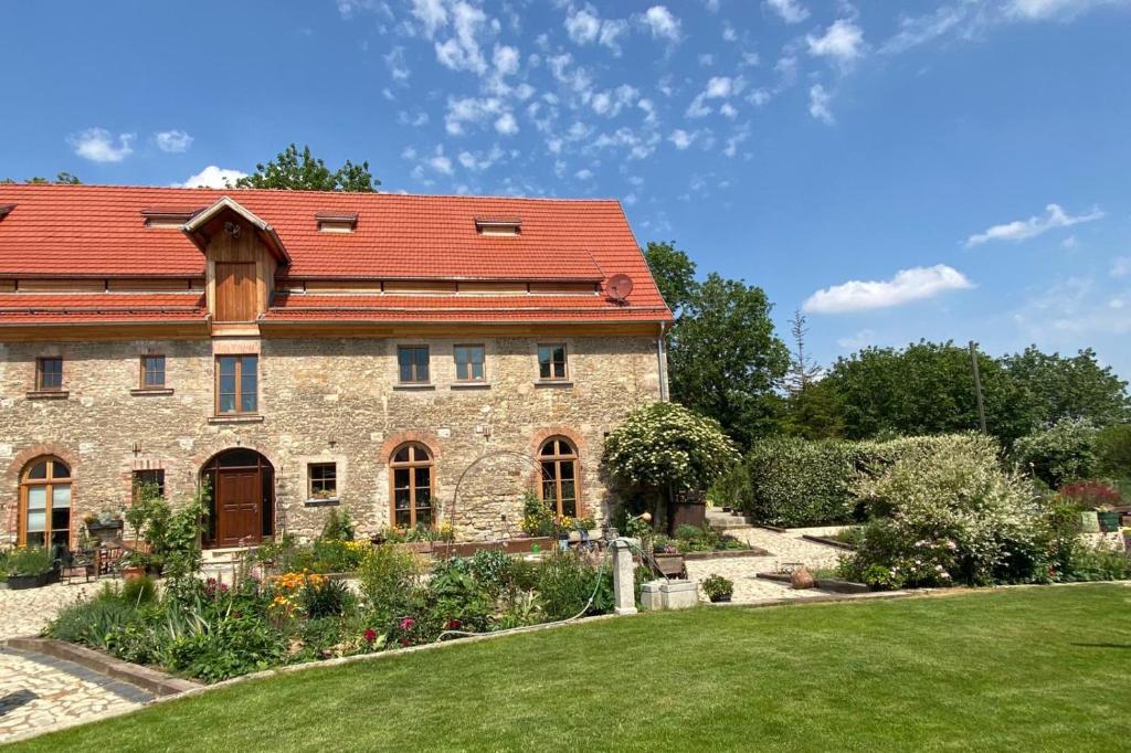 an old stone house with a red roof at Living in the old granary in Ermsleben