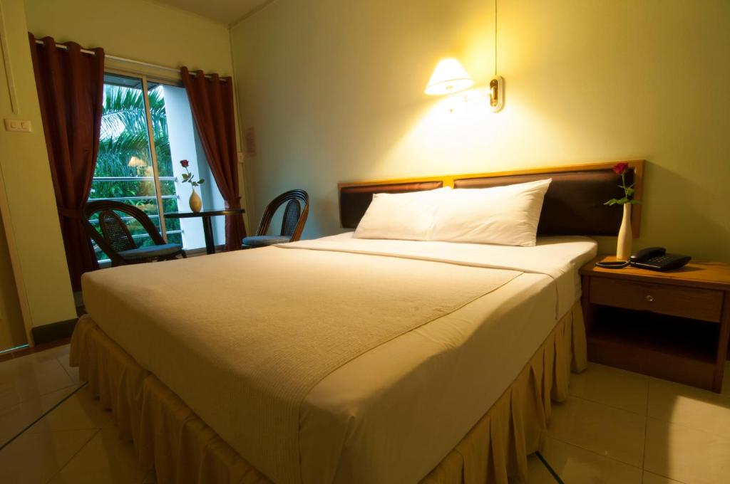 a bedroom with a large white bed and a window at Boonthavon in Chiang Mai