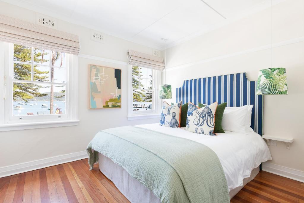 um quarto branco com uma cama grande com riscas azuis e brancas em Barrenjoey House em Palm Beach