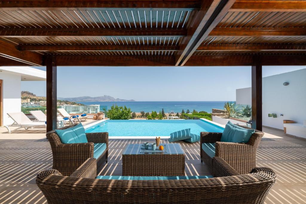 eine Terrasse mit Stühlen und einem Pool mit Aussicht in der Unterkunft Villa Milena with private pool, Vlicha beach Lindos in Lindos