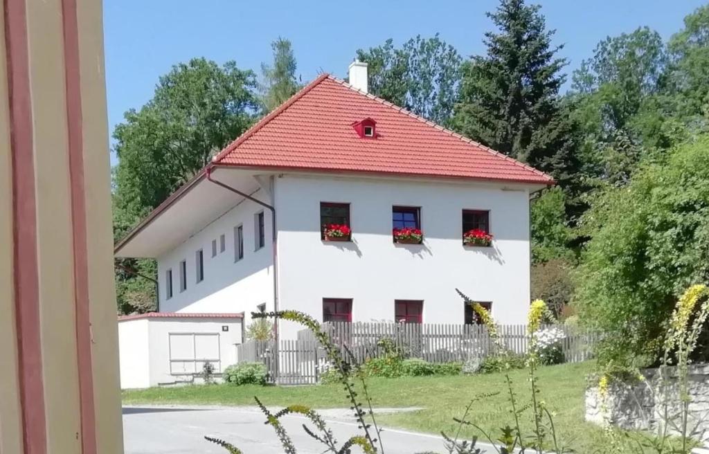 uma casa branca com um telhado vermelho e janelas em Ubytování Praschlhaus em Horní Planá