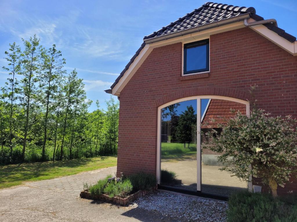 ein rotes Backsteinhaus mit einem großen Fenster darauf in der Unterkunft De Varkensstal in De Heurne