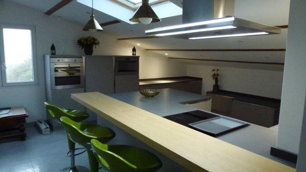una cocina con encimera y algunos taburetes verdes en L'Eterlou Saint Blaise, bel appartement neuf mansardé, en Saint-Blaise