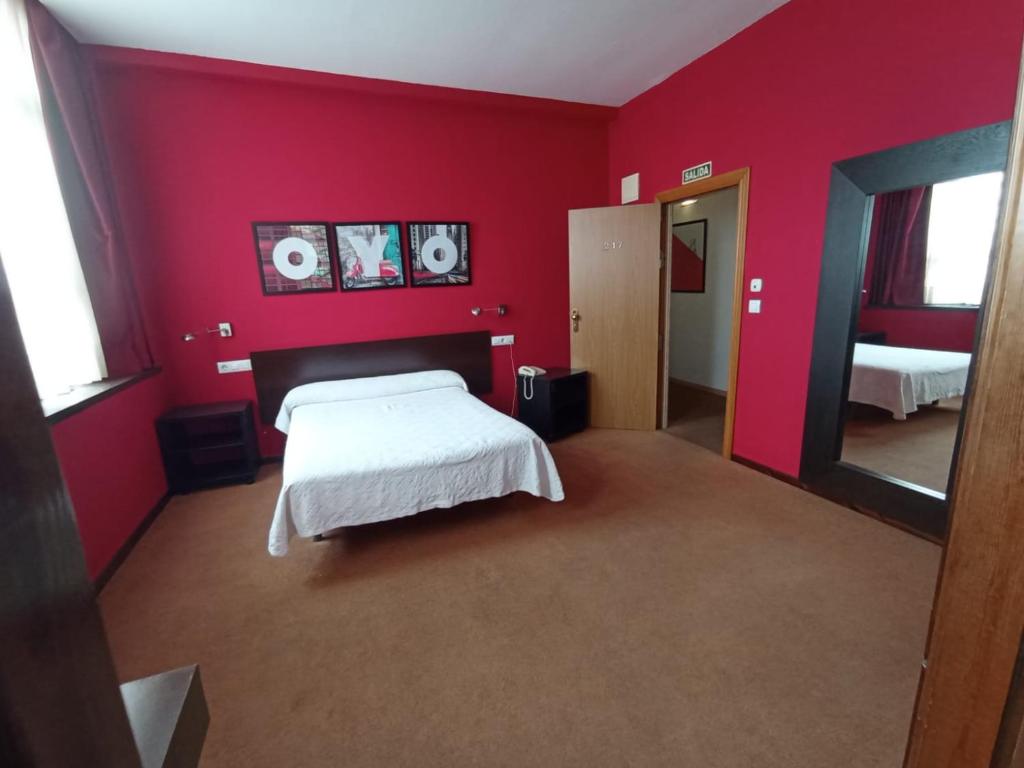 Dormitorio rojo con cama y espejo en Hotel / Restaurante LA PEPA, en Avilés