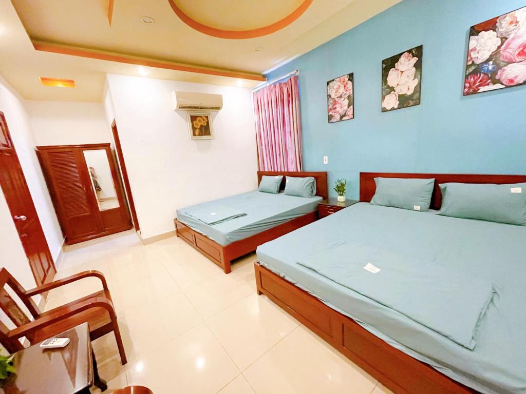 Cette chambre comprend 2 lits et une chaise. dans l'établissement GreenHome Hotel, à Hai Phong