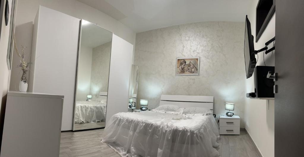 ein weißes Schlafzimmer mit einem Bett und einem Spiegel in der Unterkunft CASA DI KEKKO in Mesagne