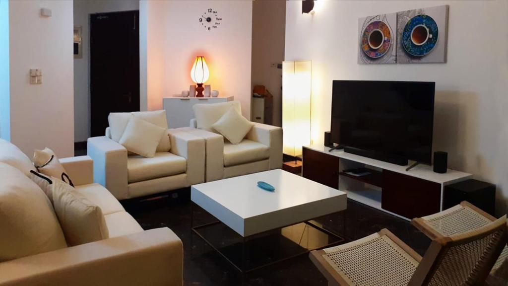a living room with a couch and a tv at Great Location Living, Modern 2-Bed Apartment with Pool & Gym Access, All Amenities in Sri Jayewardenepura Kotte