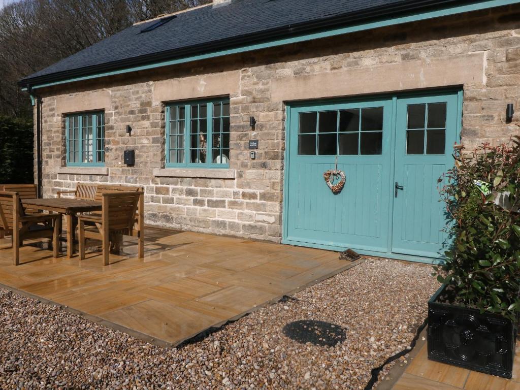 a patio with a blue door and a table and chairs at Willow Cottage in Sheffield