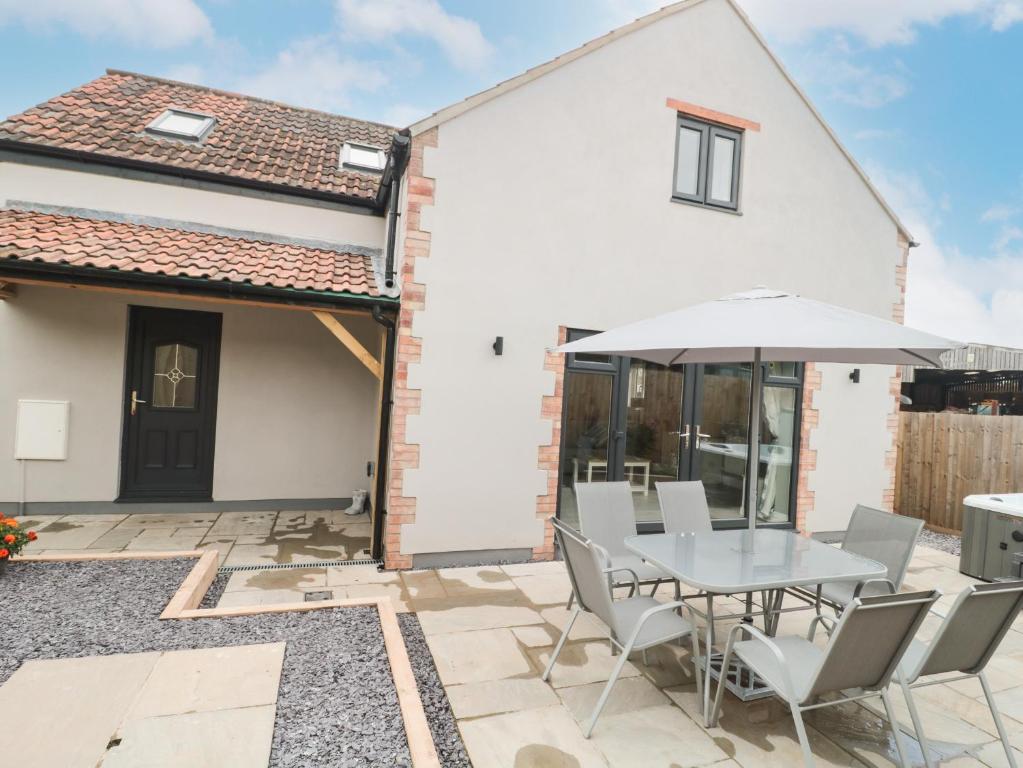 a patio with a table and chairs and an umbrella at Bramley Cottage in Langport