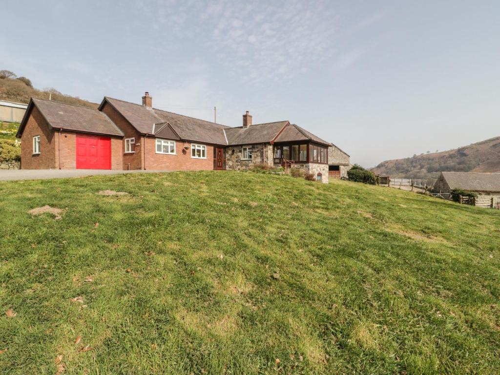 a house on top of a grassy hill at Cwm heulog in Abergele