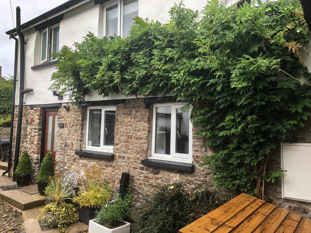 a brick house with ivy growing on it at Courtyard Cottage in Chittlehampton