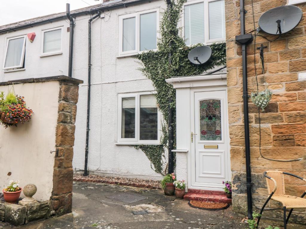 a house with a white door and ivy at Swainby Cottage in Northallerton