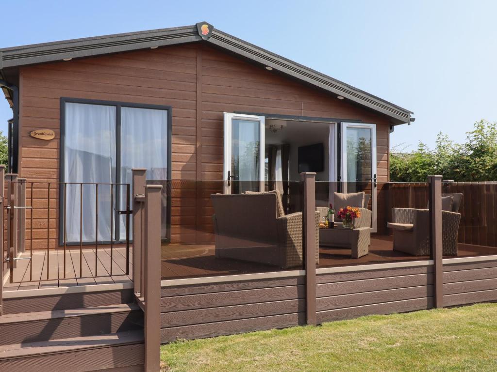 a cabin with a deck with a sliding glass door at Bramblewick in Runswick