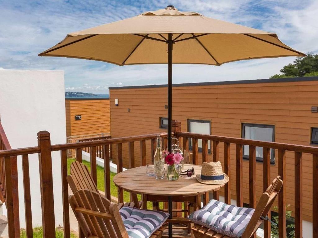 einen Holztisch mit Sonnenschirm auf dem Balkon in der Unterkunft Egret in Brixham