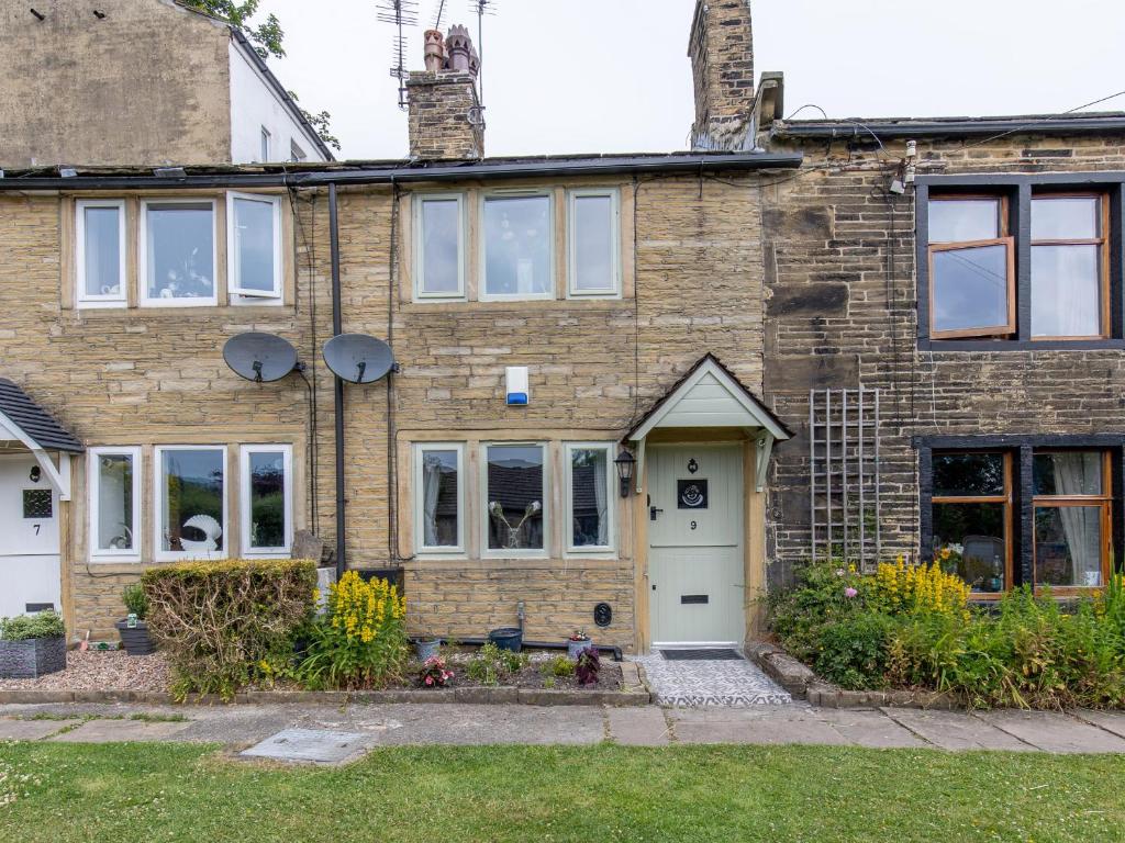 una vieja casa de ladrillo con una puerta blanca en Mischa Cottage, en Bradford