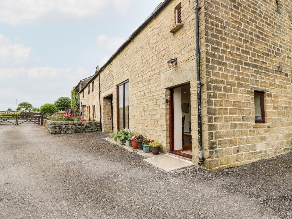 un edificio de ladrillo con macetas en el costado en The Barn at Heath Hall Farm en Sowerby Bridge