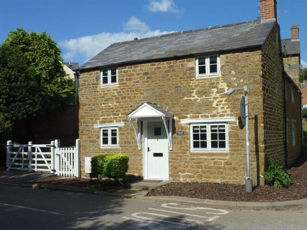 a small brick house with a white door at Hollytree Cottage in Banbury