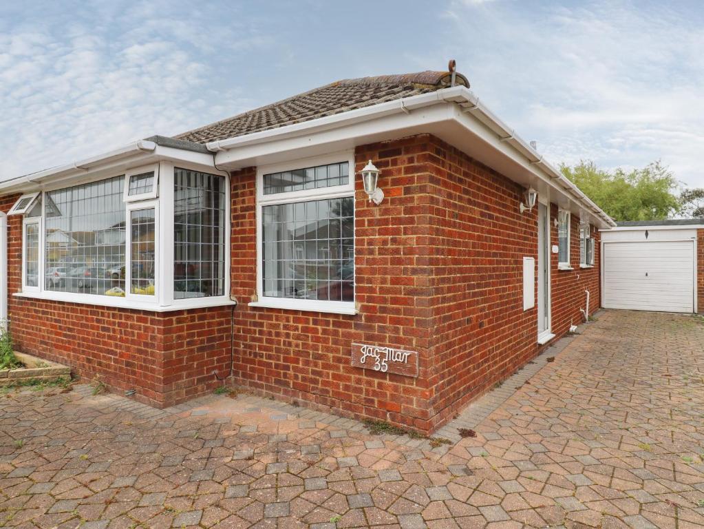 a brick house with white windows and a brick driveway at 35 Seabourne Way in Dymchurch