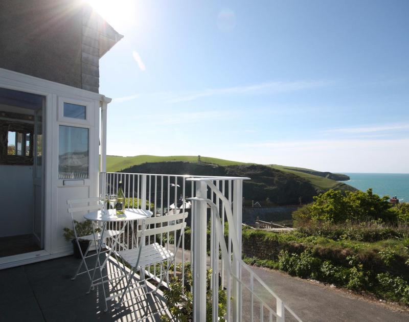 a white porch with a table and chairs on a house at Castaway in Port Isaac