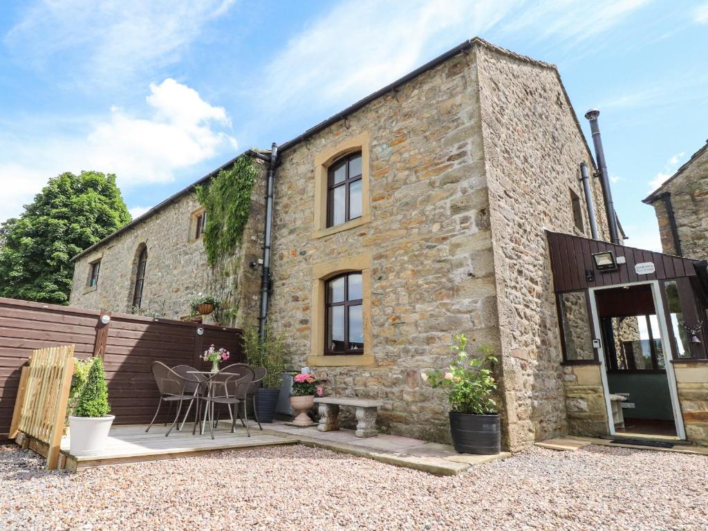 an old stone building with a patio and a table at Sandholme Cottage in Skipton