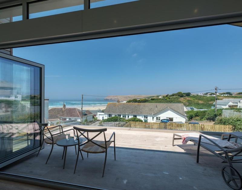 a patio with a table and chairs and a view of the ocean at Point Break in Polzeath