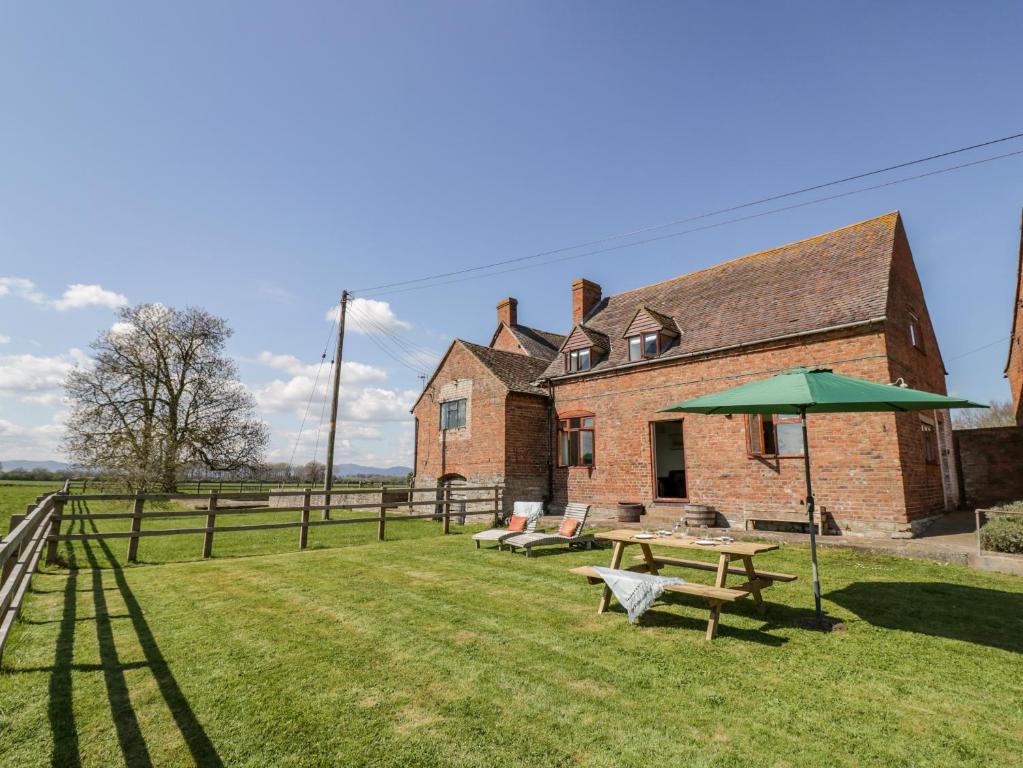 a picnic table and an umbrella in front of a building at Manor Farm Cottage in Worcester