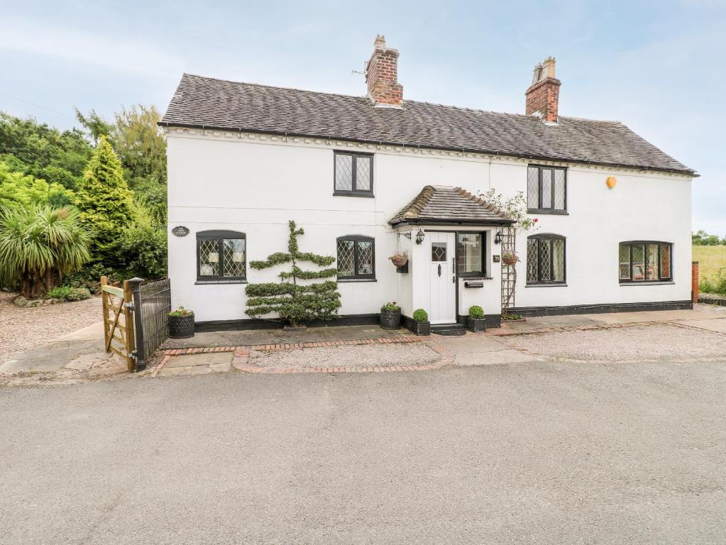 une maison blanche avec des fenêtres noires et une allée. dans l'établissement The White Cottage, à Burton-on-Trent