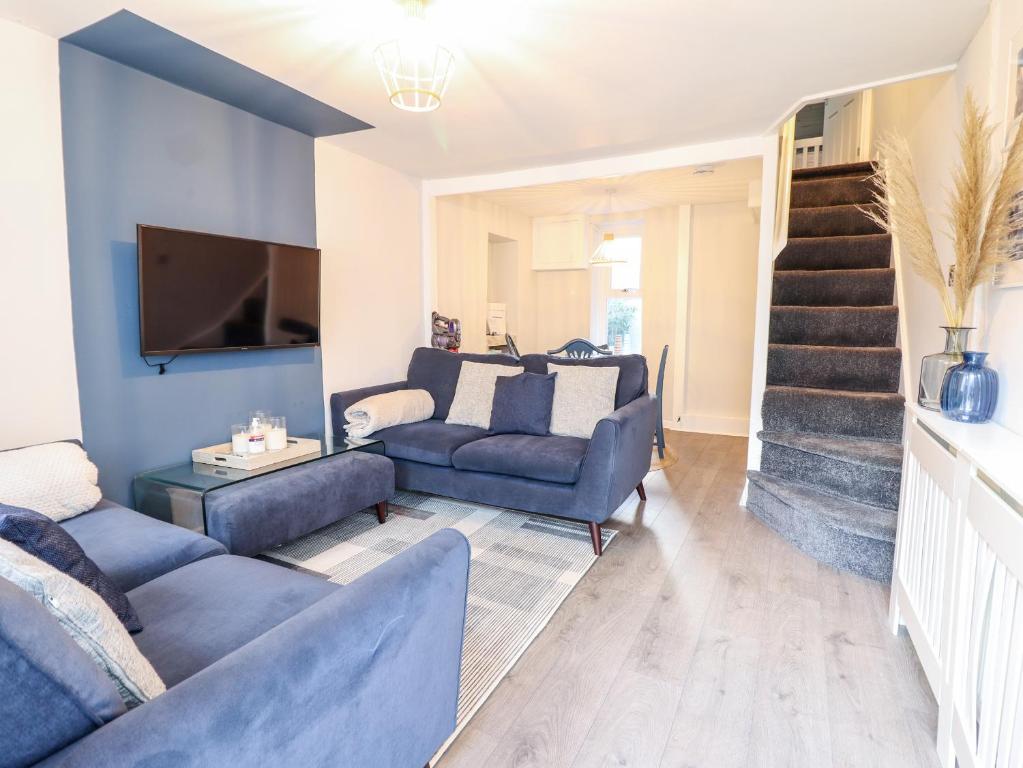 a living room with blue furniture and a staircase at Driftwood Terrace in Porthmadog