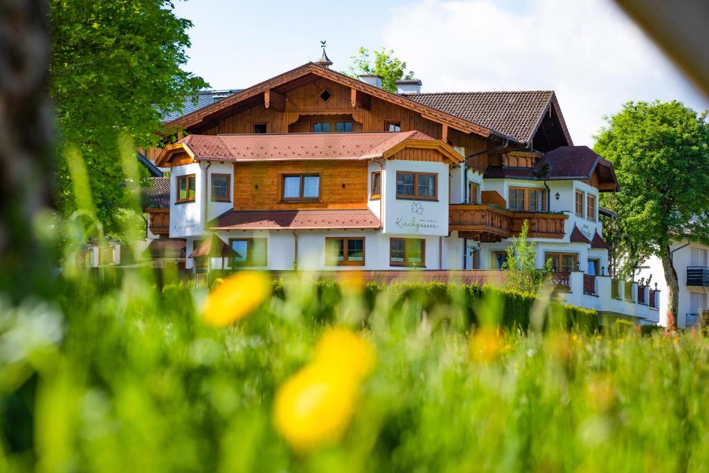 a large house in the middle of a field of grass at Landhaus Kirchgasser in Ramsau am Dachstein