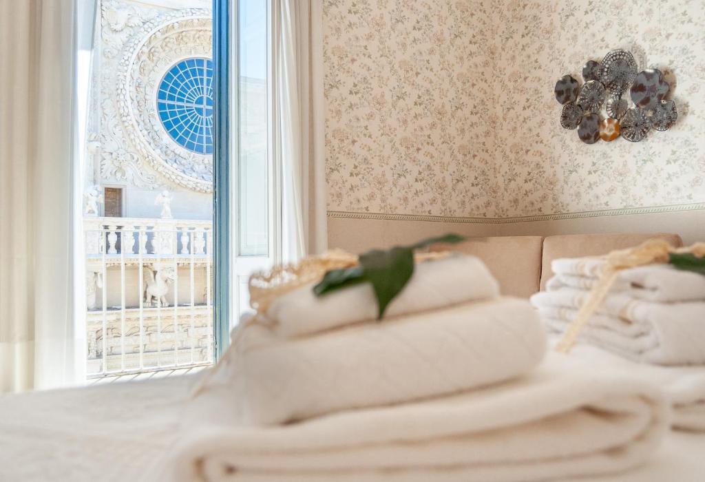 una pila de toallas en una cama frente a una ventana en B&B Risveglio col Rosone en Lecce
