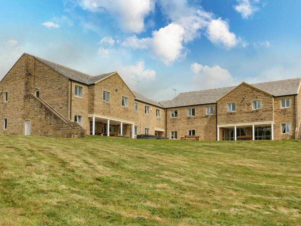 a large brick building on a grass field at Myddelton Grange in Ilkley