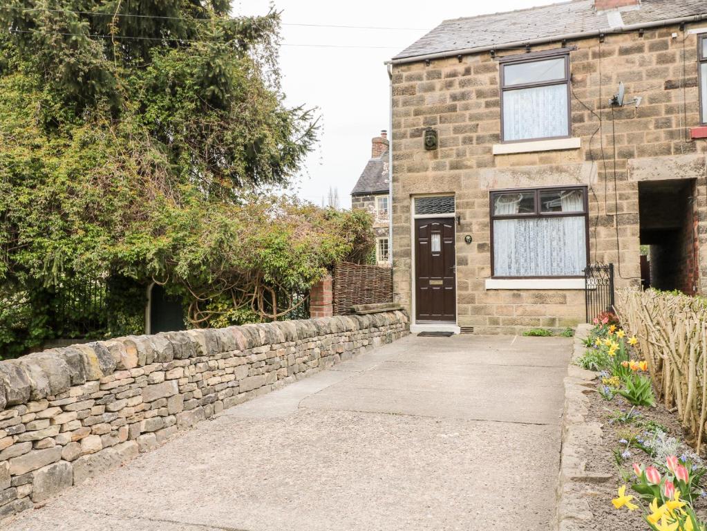 a brick house with a stone wall and a driveway at Halfways in Belper