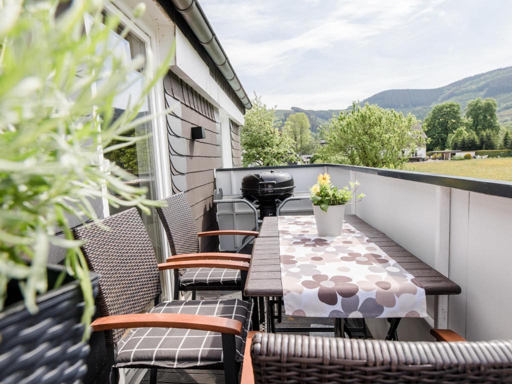 a balcony with a table and chairs and mountains at Ferienwohnung Kurparkblick Sauerland in Lennestadt