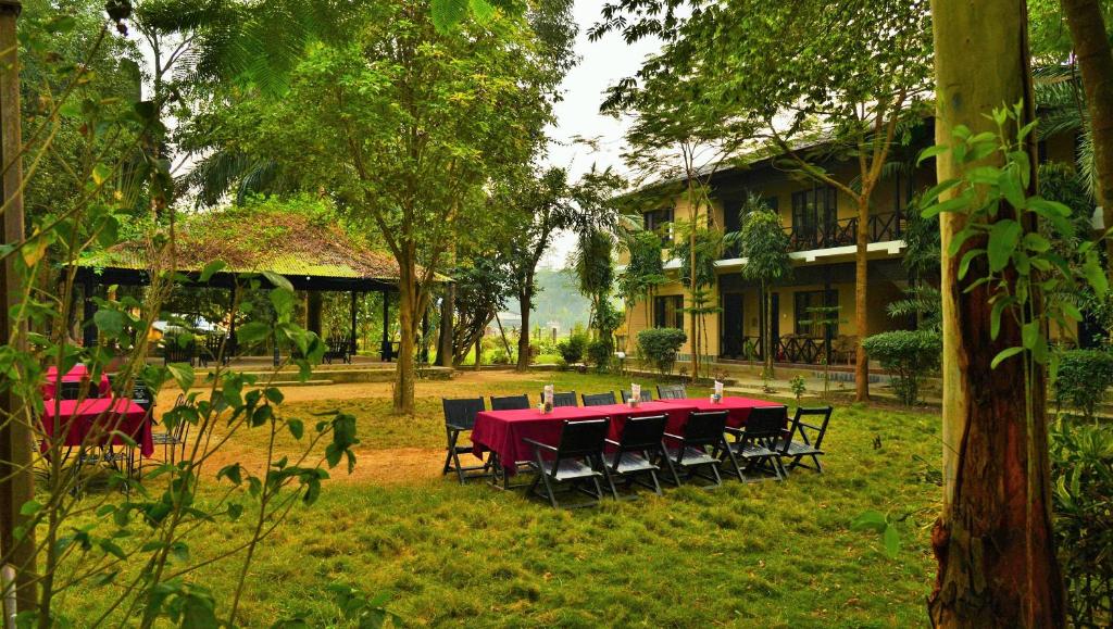 un tavolo rosso e sedie nel cortile di una casa di Hotel Parkside & Swimming Pool-Between Greenery and Azure ,Your Perfect Retreat a Chitwan