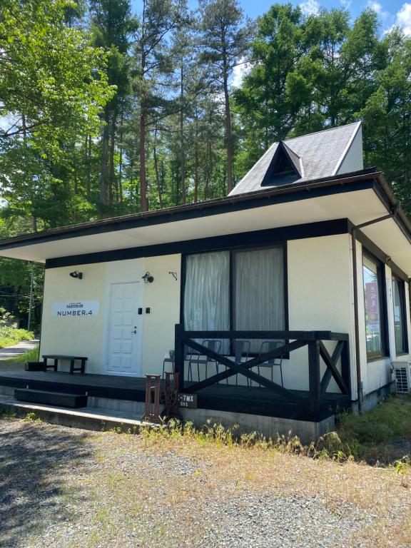 ein kleines weißes Cottage mit einer Veranda und einer Tür in der Unterkunft SAMURISE No.4 in Fujikawaguchiko