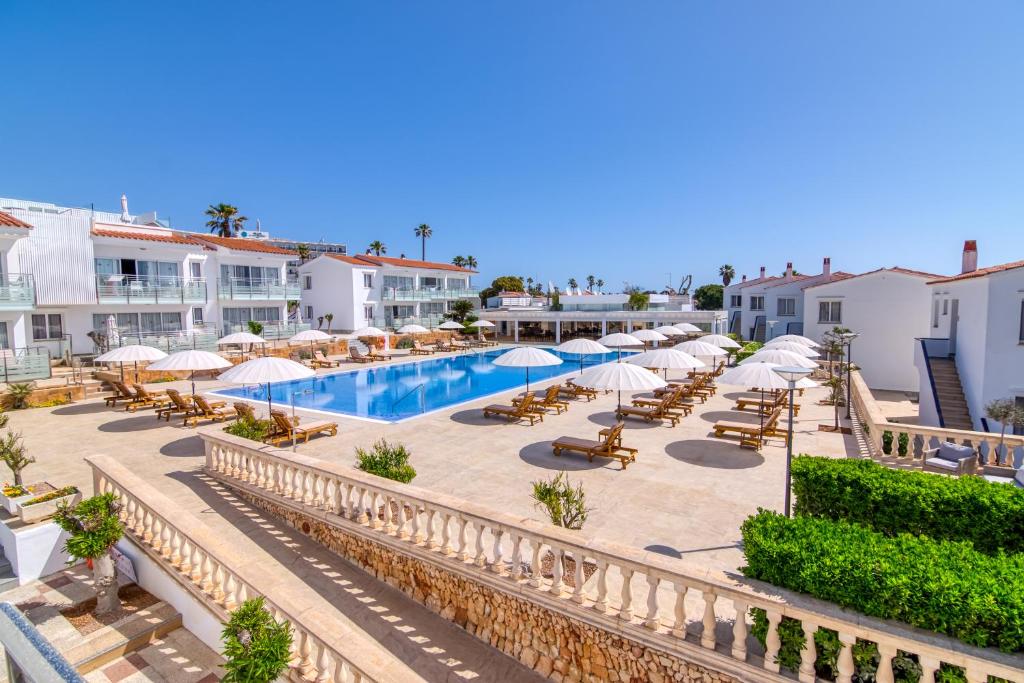 a resort with a pool and chairs and umbrellas at Naranjos Resort Menorca in S'Algar